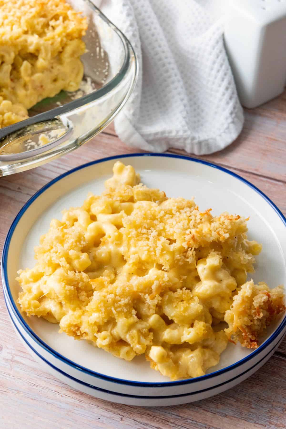 Cheesy homemade macaroni and cheese served on a white plate with a blue rim.