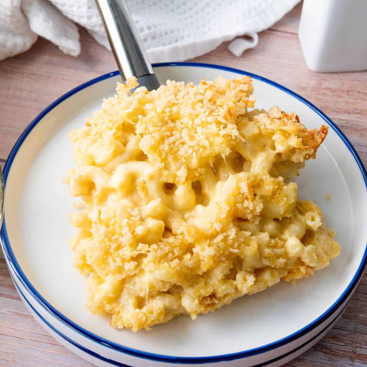Creamy Mac & Cheese with a golden breadcrumb topping, served on a cozy wooden table.
