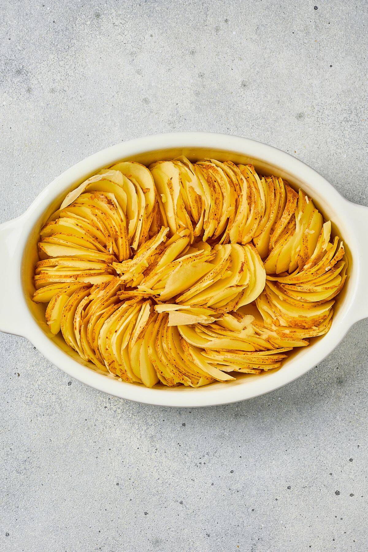 A delicious baked potato dish with thinly sliced potatoes layered with cheese in a white baking dish.