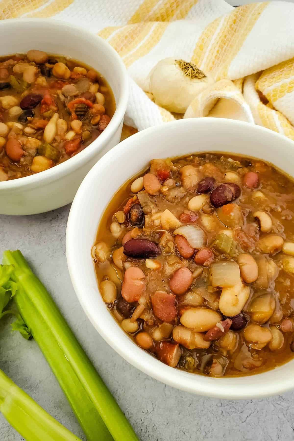 Rich bean soup with tomatoes, onions, and spices in white bowls.