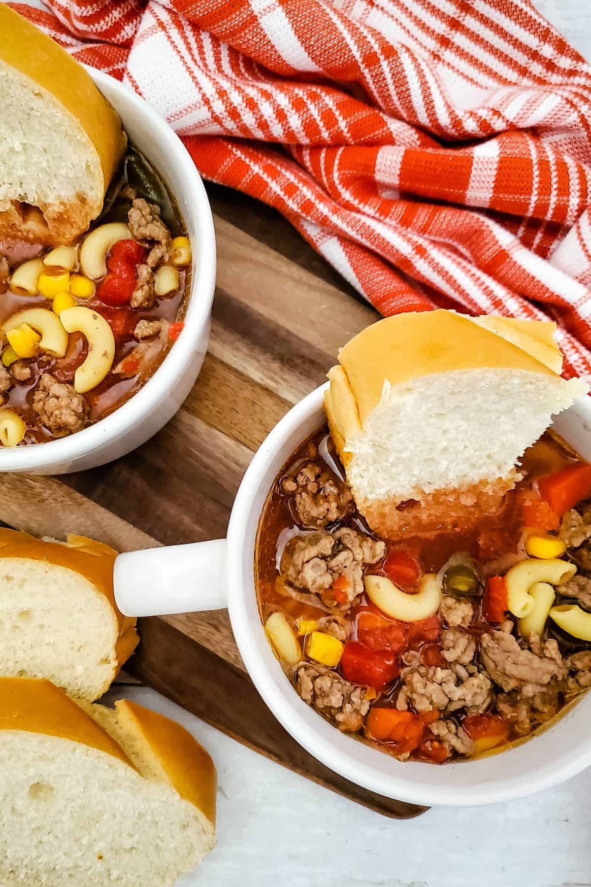 Delicious chicken noodle soup served in white bowls with bread slices on rustic wooden tray. Perfect comfort food for chilly days.