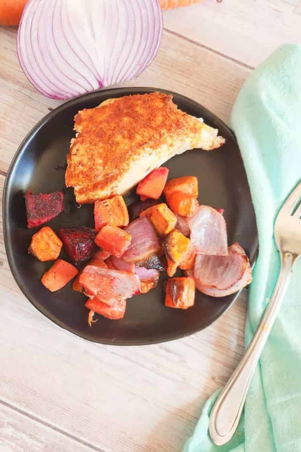 Baked fish fillet with crispy golden crust served alongside roasted sweet potatoes and onions.