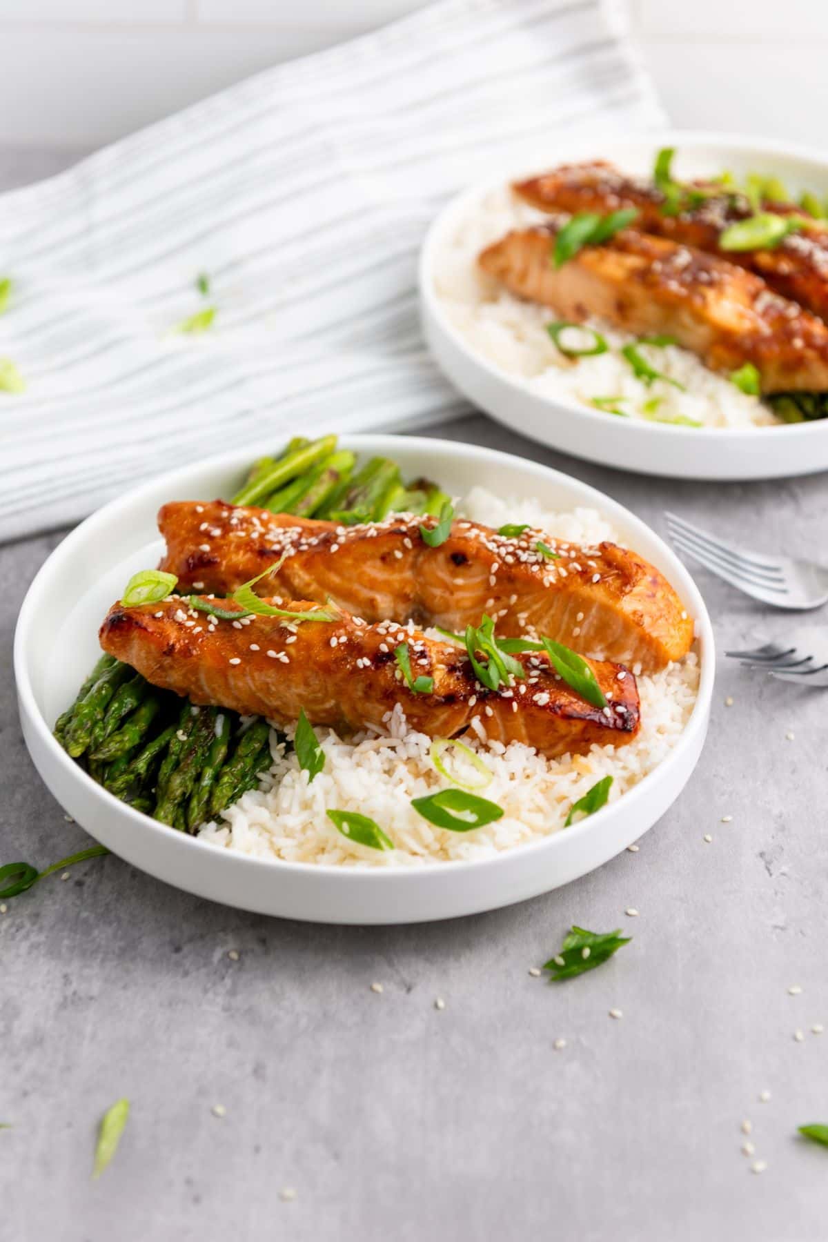 Delicious salmon fillets served over rice with green asparagus and garnished with green onions.