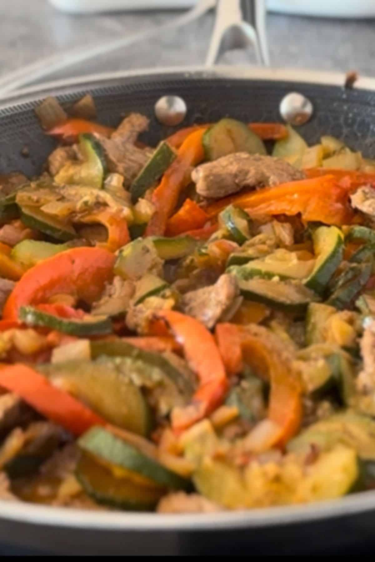 Colorful sautéed zucchini, carrots, and peppers in a black skillet.