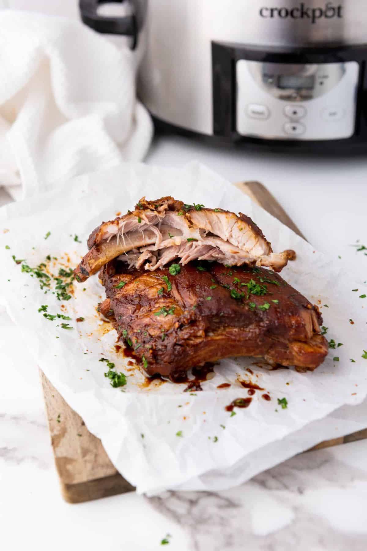 Delicious herb-crusted roast pork resting on parchment paper, ready to serve, with a Crockpot in the background hinting at homemade cooking.