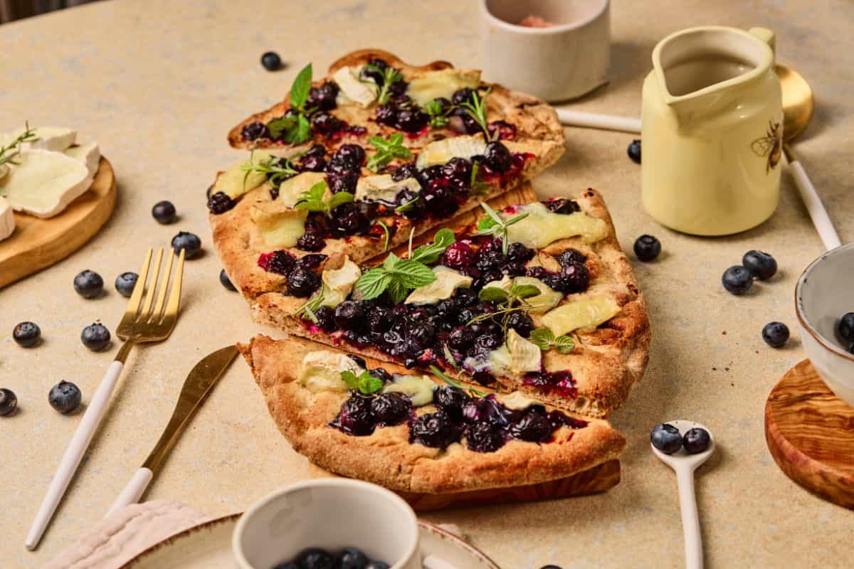 Fresh blueberry and blackberry dessert pizza with mint, cheese, and flaky crust. Perfect for breakfast or brunch.