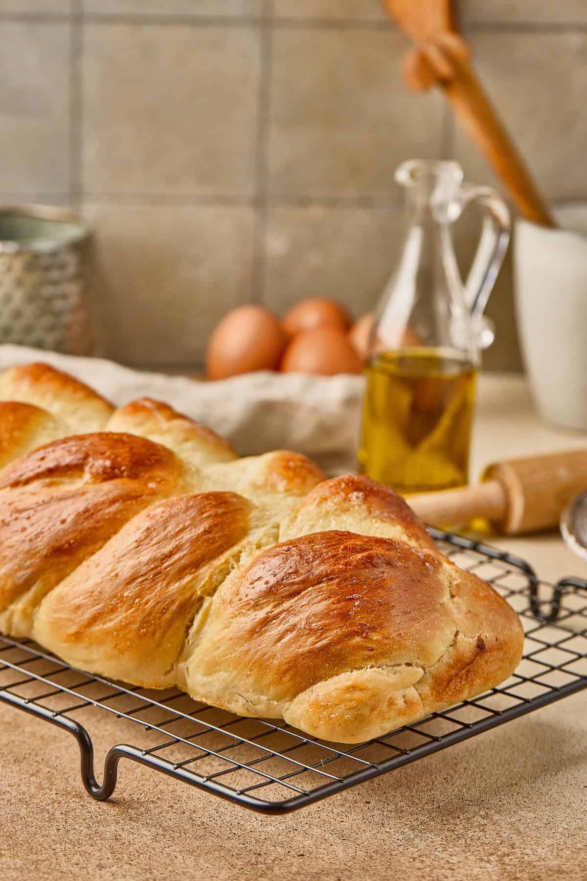 Delicious homemade bread crust on a cooling rack with eggs and oil in the background.