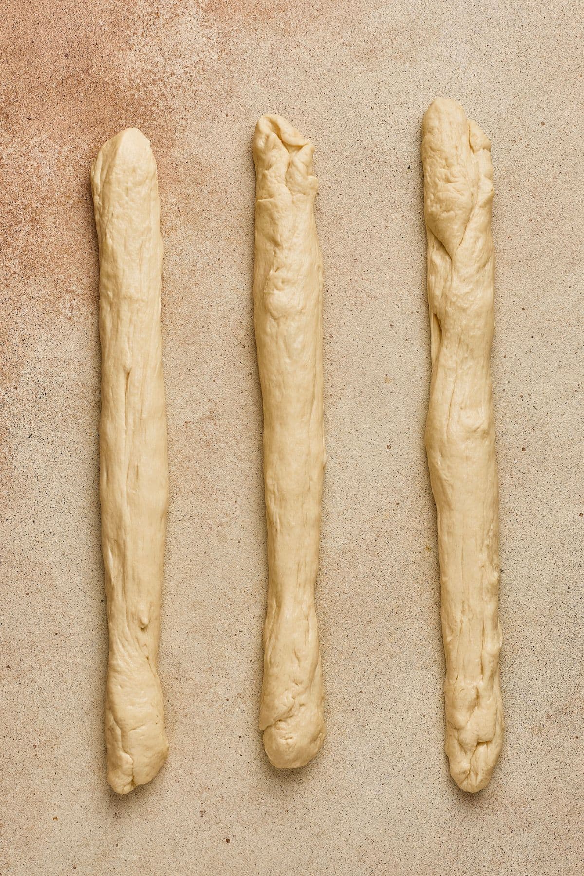 Three homemade breadsticks with irregular shapes and textures.