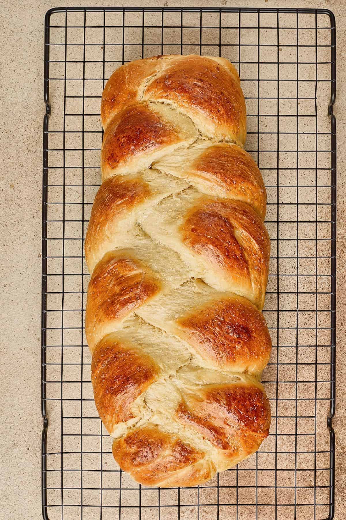 Golden brown bread on cooling rack, freshly baked, soft and fluffy interior.