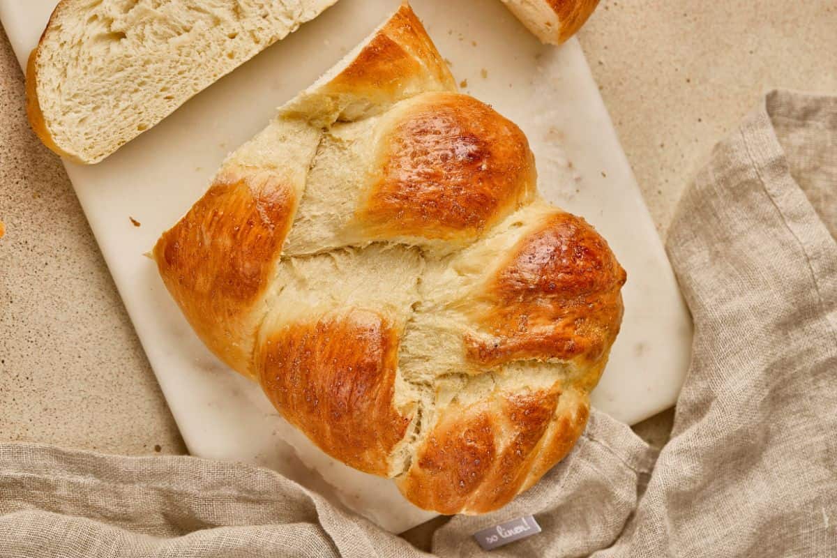 Golden, flaky croissant bread with a soft interior on a marble board.