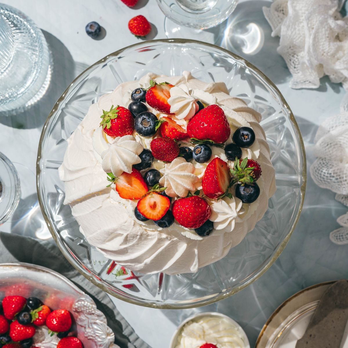 Top view of pavlova topped with whipped cream and fresh berries.
