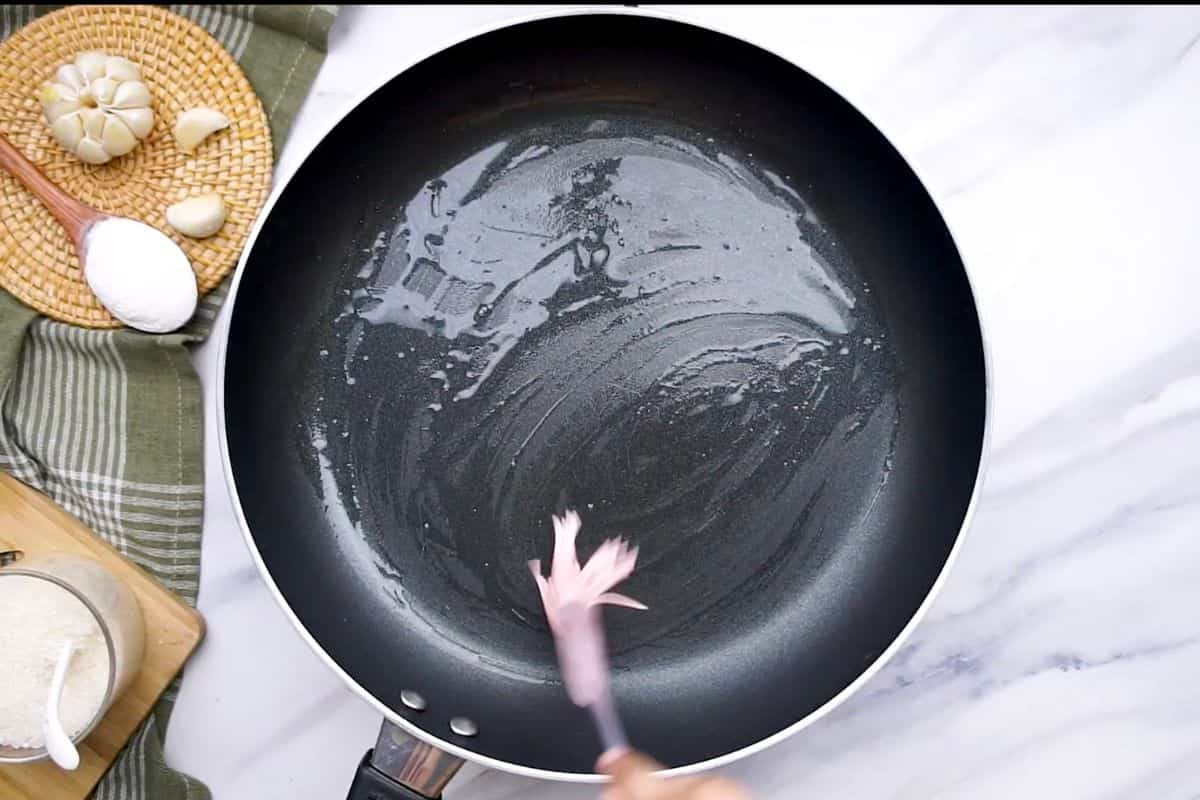 Non-stick frying pan with heat-resistant handle and oil residue.