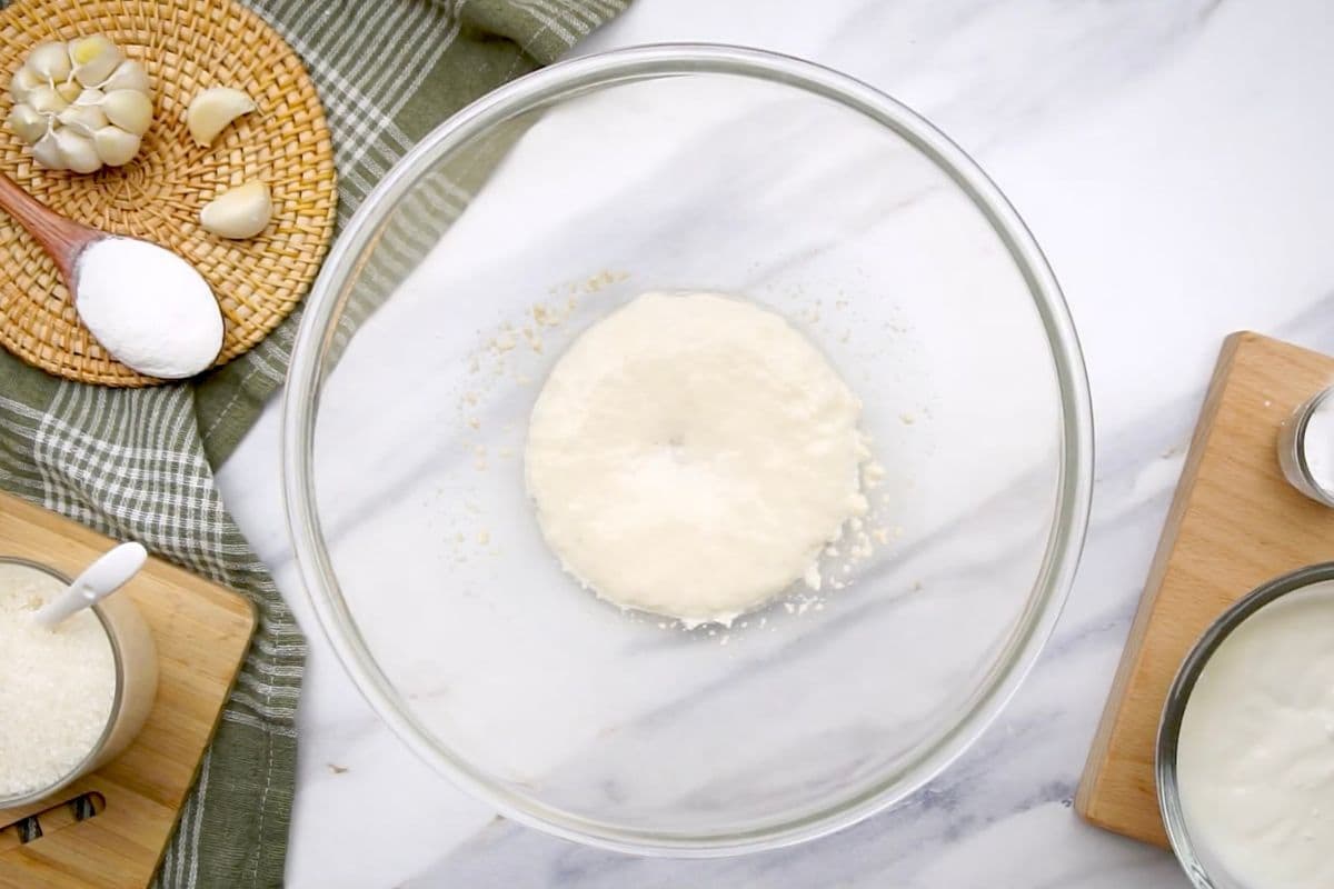 Fresh garlic, salt, and shredded cheese nearby for cheese ball recipe.