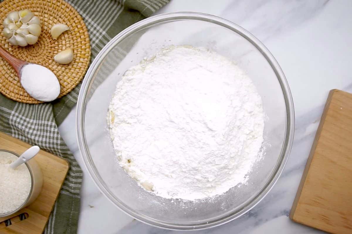 Fresh garlic cloves, flour and baking soda on board.