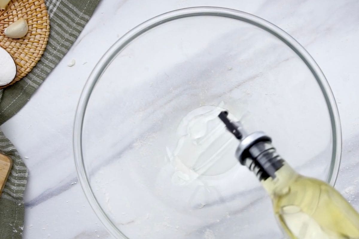 Homemade whipped cream in a clear glass bowl with a hand mixer for baking or desserts.
