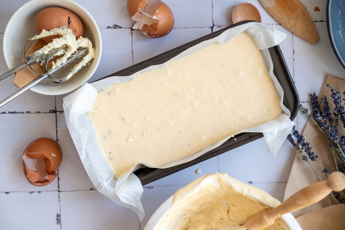 Creamy cake batter in baking pan with parchment paper.