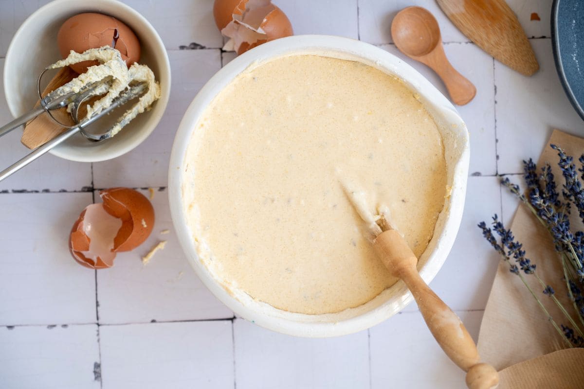 Creamy cake batter in a white mixing bowl with baking ingredients around.