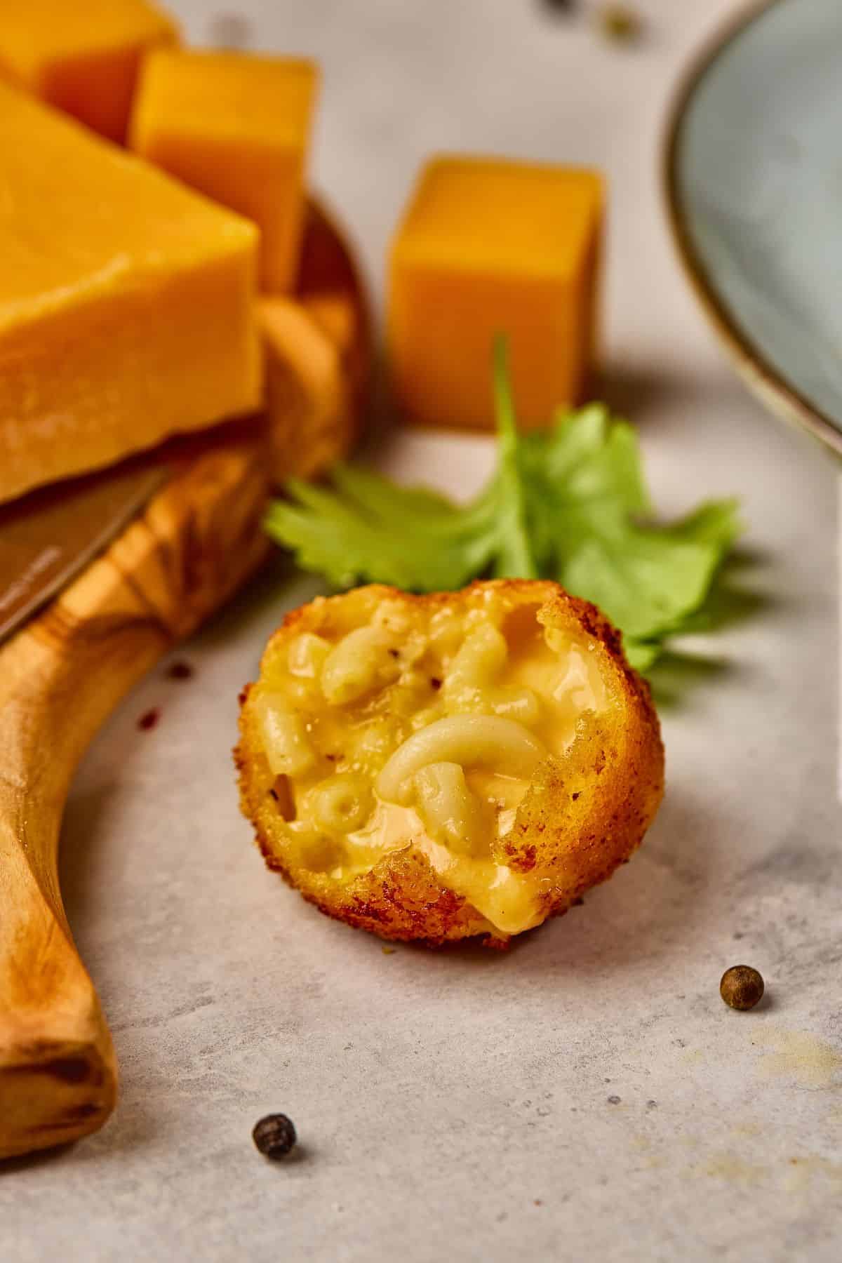 Delicious stuffed macaroni and cheese croquette with cheesy filling, served with cheese and a leafy garnish.
