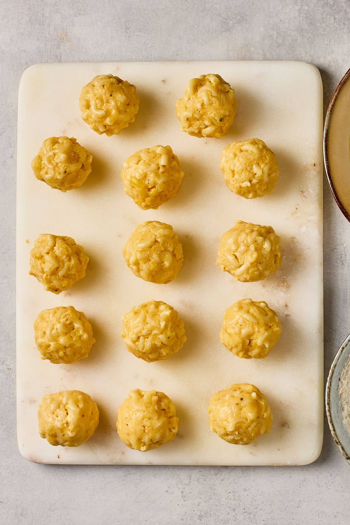Creamy cheese balls with nuts on a white cutting board.