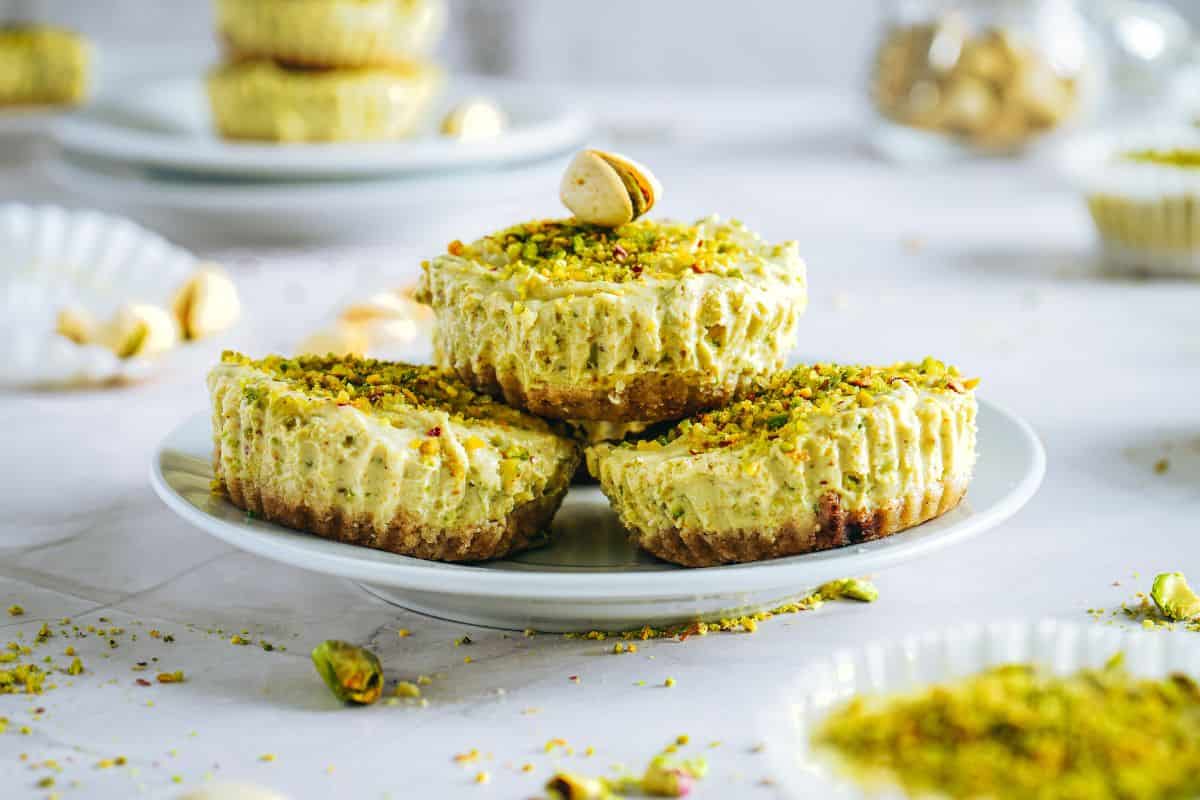 Delicious pistachio-topped cheesecake bites on a white plate, perfect for dessert or festive gatherings.