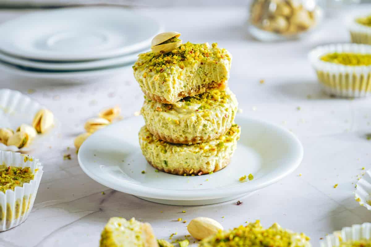Delicious pistachio cheesecake bites topped with crushed pistachios on a white plate.