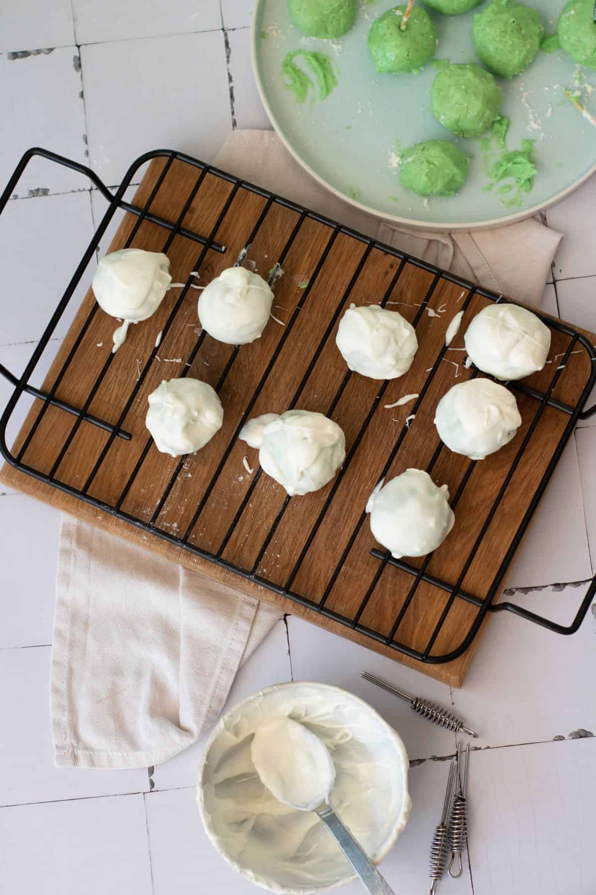 Creamy white chocolate-covered cake pops on a wire rack, ready to set.