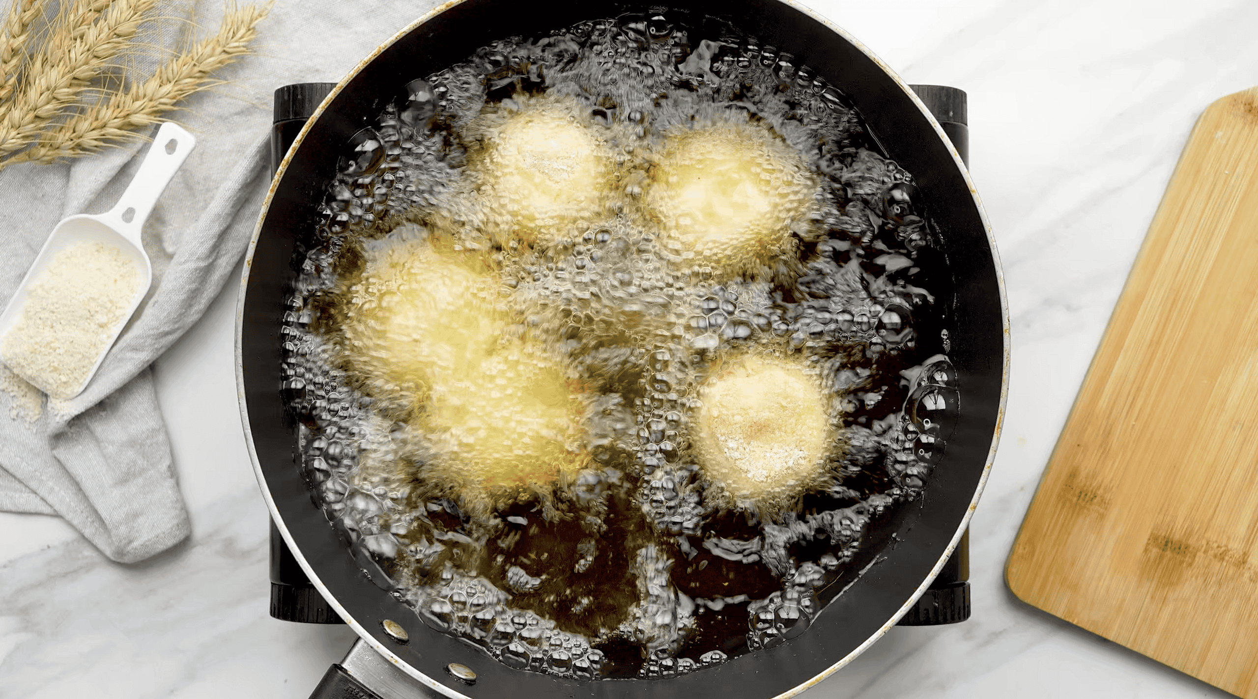 Cheese balls frying in hot oil, close-up shot of crispy snack preparation.