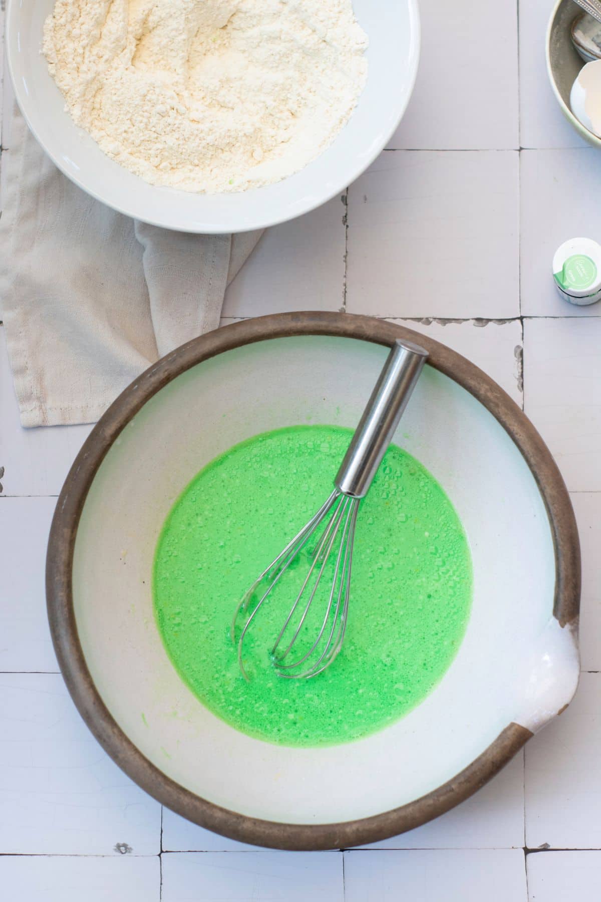 Bright green cake batter in a mixing bowl with a whisk, ready to bake.