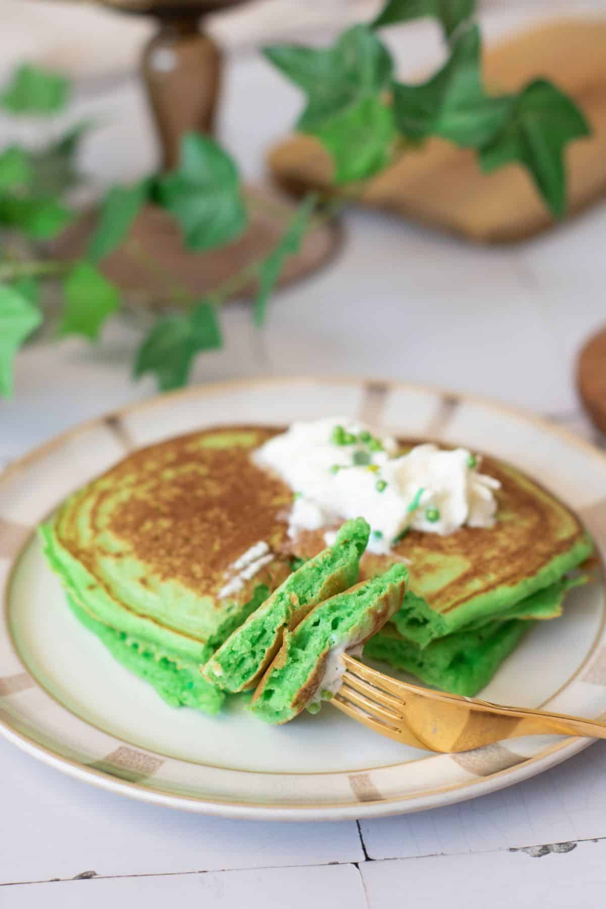 Bright green fluffy pancakes topped with whipped cream and chives, on a stylish plate. Ideal breakfast for kids and family.