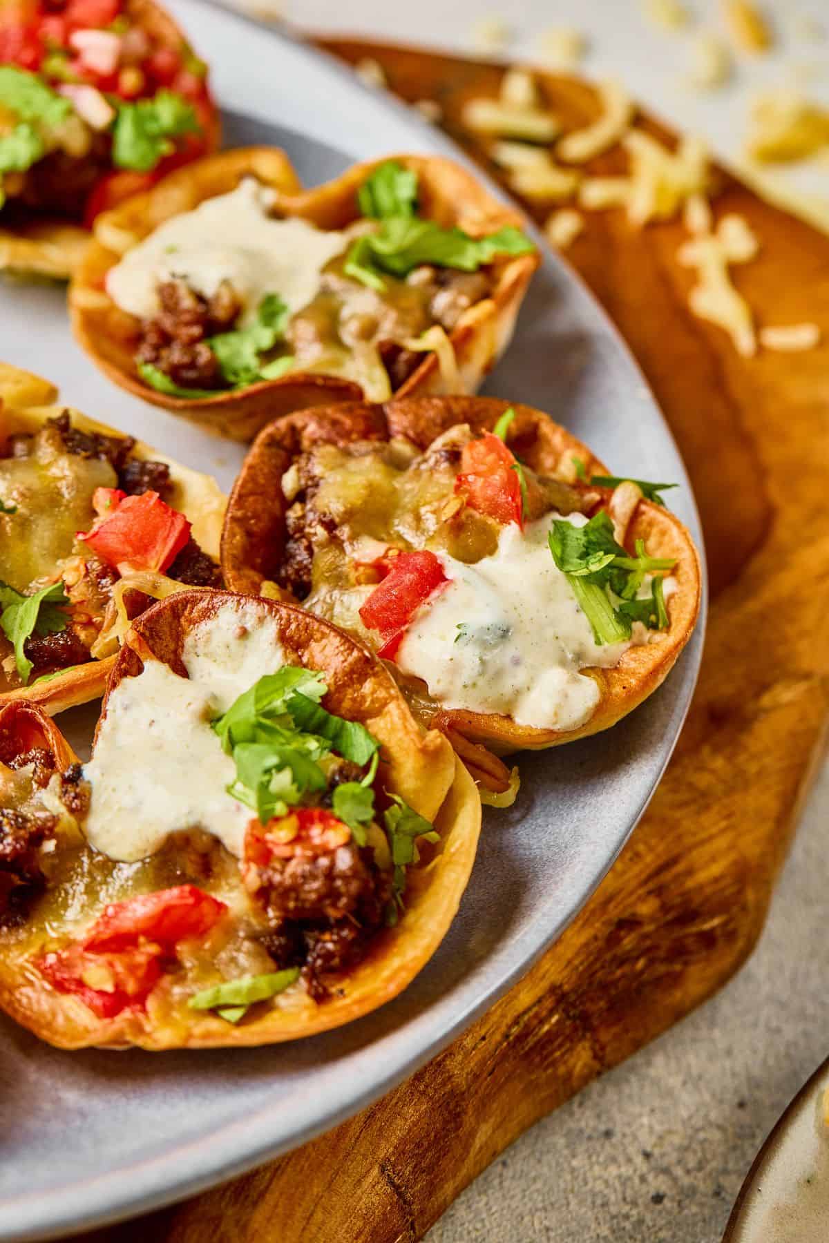 Freshly baked nachos topped with cheese, tomatoes, ground beef, sour cream, and cilantro. Perfect party snack or appetizer.