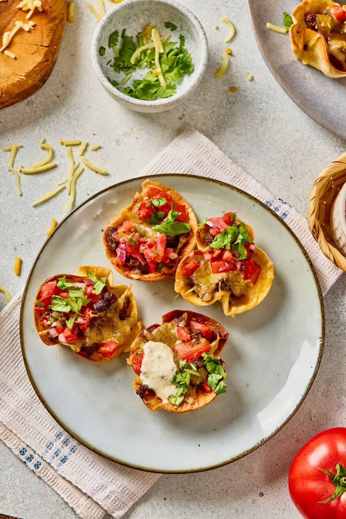 Delicious Taco stuffed peppers topped with cheese, salsa, and fresh herbs on a white plate.