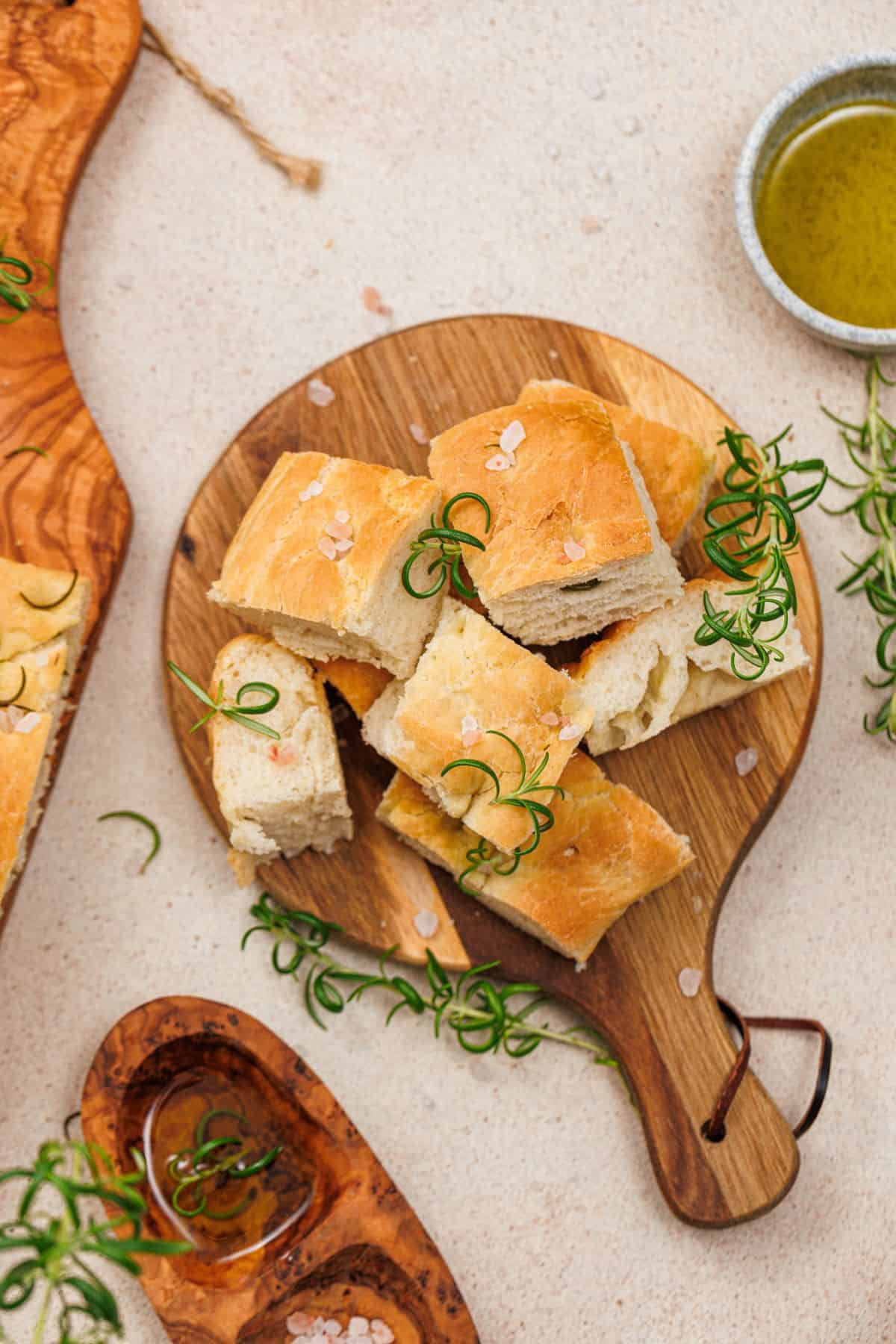 Delicious homemade bread topped with sea salt and fresh rosemary on a wooden serving board.