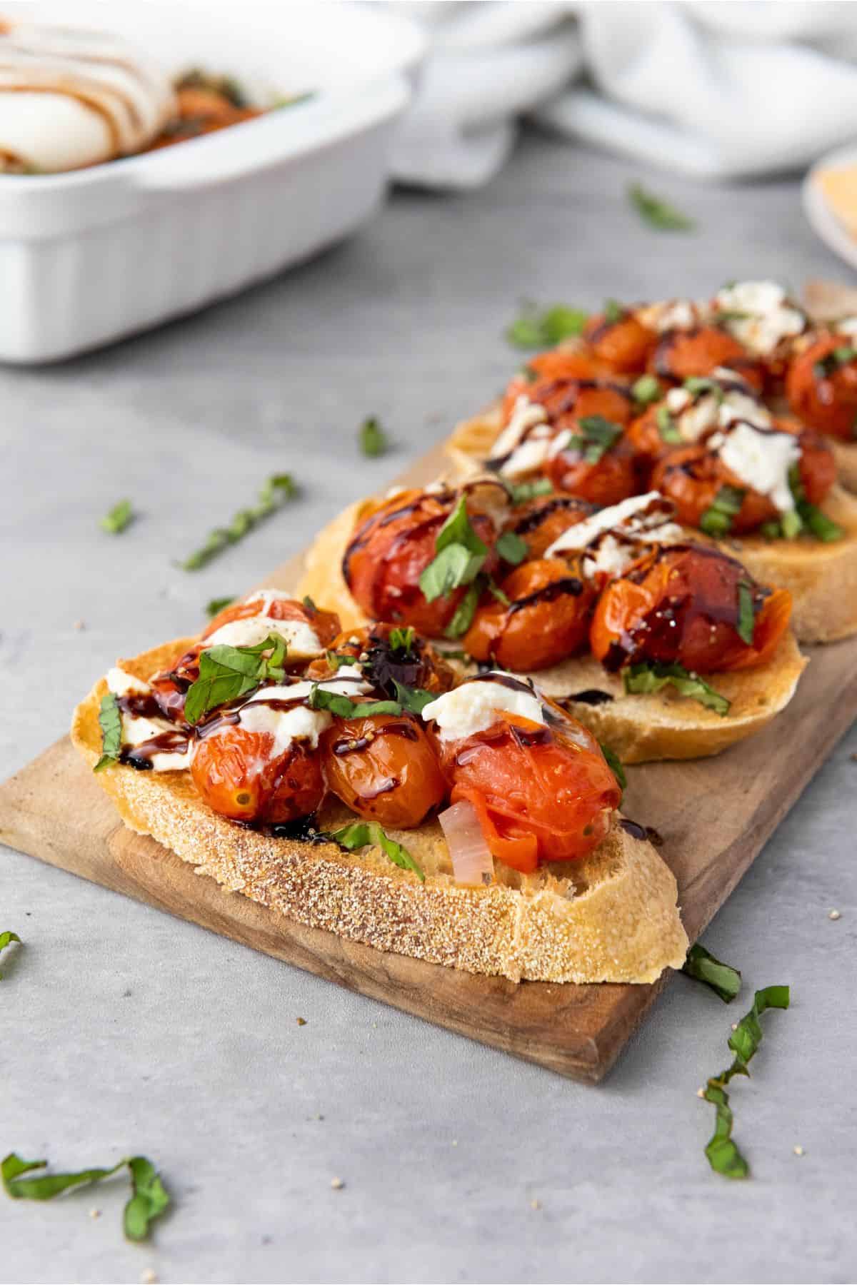 Sliced baguette topped with roasted cherry tomatoes, fresh basil, mozzarella, and balsamic glaze.